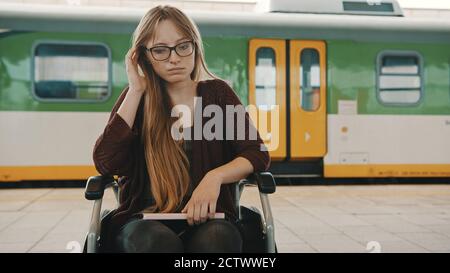 Junge behinderte Frau im Rollstuhl verlor den Zug. Hochwertige Fotos Stockfoto