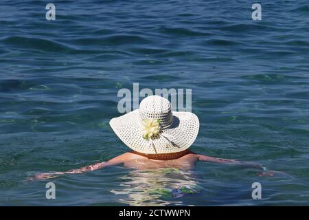 Frau in Sonnenhut schwimmen im blauen Meer. Entspannung auf dem Wasser, Strandurlaub