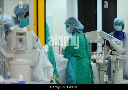 Im Operationssaal. Weibliche Chirurgen in der Maske über Gesicht in der Nähe der Patientenplatte stehen und desinfizieren Hände. Ukrainisches Kinderkardienzentrum Stockfoto