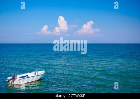 Das kleine Motorboot ist auf dem wunderschönen türkisfarbenen, friedlichen Meer vor Anker. Stockfoto