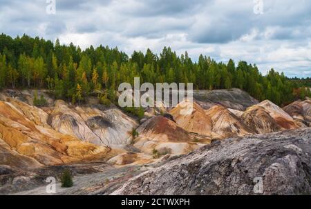 Ungewöhnlich schöne Herbstlandschaft mit roten Seen, bunten Hängen und Wald. Ural Mars. Graue Wolken bewegen sich im bewölkten Himmel. Stockfoto