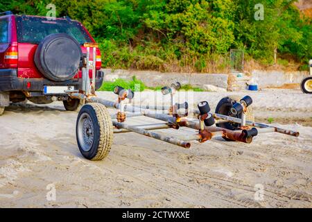 Ein Auto mit Anhänger ist am Strand für das Entladen von kleinen Motorbooten im Meerwasser geparkt. Stockfoto