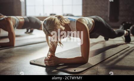 Zwei Young Fit Atletic Frauen halten eine Plank-Position, um ihre Kernkraft auszuüben. Sie sind erschöpft und kämpfen mit dem Training. Sie Stockfoto
