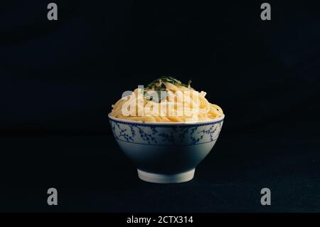 Spaghetti-Schüssel mit Petersilie auf schwarzem Hintergrund Stockfoto