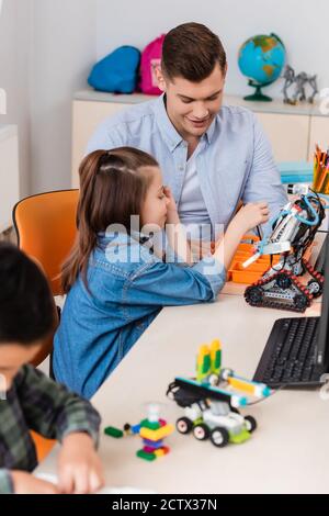 Selektiver Fokus von Lehrer und Schulmädchen Modellierung Roboter in der Nähe von Computer In der MINT-Schule Stockfoto