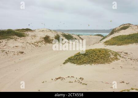 Sandstraße zwischen Dünen zum Strand, Kitesurfer im Hintergrund Stockfoto