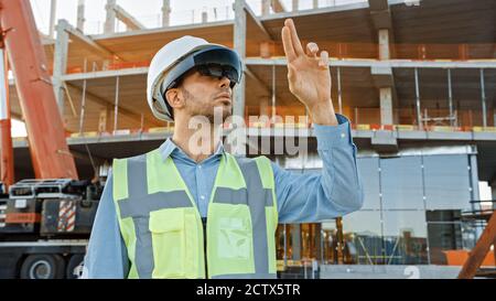 Futuristischer Architekturingenieur mit Augmented Reality-Headset und Gesten zur Steuerung der industriellen Baustellenbaustelle. Zoll Stockfoto