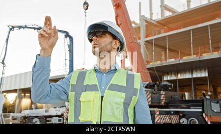 Futuristischer Architekturingenieur mit Augmented Reality-Headset und Gesten zur Steuerung der industriellen Baustellenbaustelle. Zoll Stockfoto
