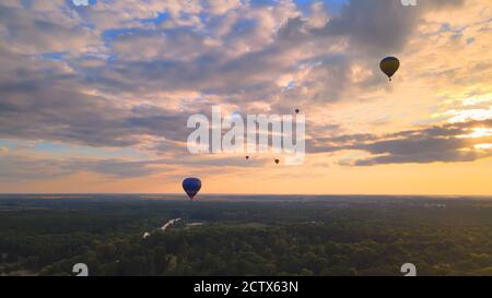 Luftdrohne Ansicht der bunten Heißluftballon fliegen über grünen Park in kleinen europäischen Stadt bei Sonnenuntergang im Sommer, Kiew Region, Ukraine Stockfoto
