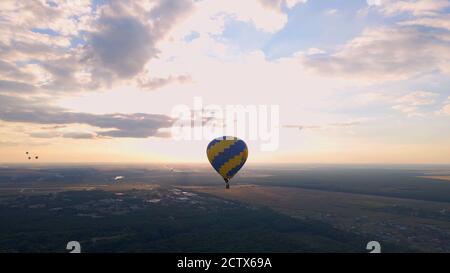 Luftdrohne Ansicht der bunten Heißluftballon fliegen über grünen Park in kleinen europäischen Stadt bei Sonnenuntergang im Sommer, Kiew Region, Ukraine Stockfoto