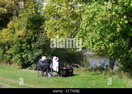 Ein älteres Paar, das an einem späten Sommertag an der Themse in Runnymede sitzt, Egham Surrey England Stockfoto