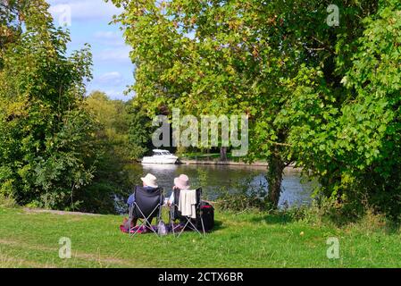 Ein älteres Paar, das an einem späten Sommertag an der Themse in Runnymede sitzt, Egham Surrey England Stockfoto