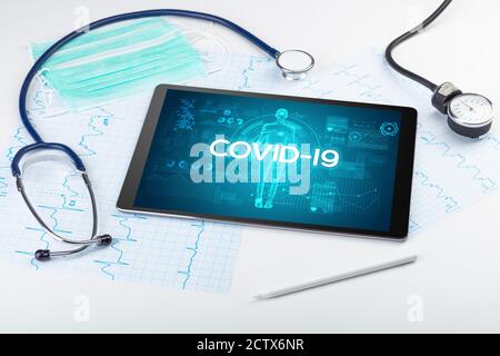 Tablett-pc und Arztwerkzeuge mit COVID-19-Beschriftung, Coronavirus-Konzept Stockfoto