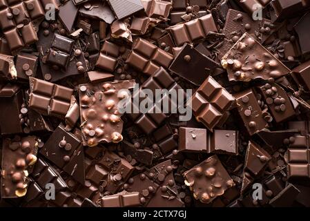 Verschiedene Schokoladenriegel und Brocken, Hintergrund. Flaches Lay mit einer Vielzahl von Schokoladenarten. Köstliches Kakao-Dessert. Backen Schokolade Sammlung. Stockfoto