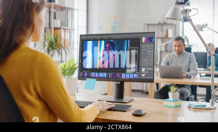 Über die Schulter: Creative Young Woman Digital Editor arbeitet in Photo Editing Software auf ihrem Personal Computer mit Big Display. Im Hintergrund Stockfoto