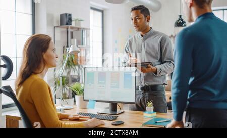 Drei Mobile Software-Entwickler arbeiten an Desktop-Computer, sie diskutieren Smartphone Application Design verwenden Touch Screen Digital Tablet. Modern Und Stilvoll Stockfoto