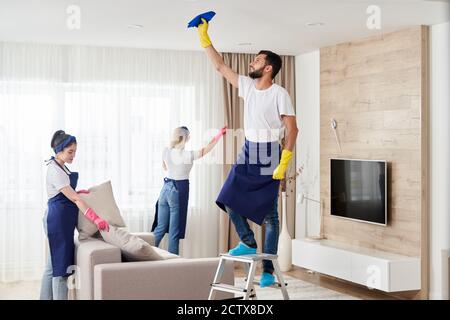 Professionelles Reinigungsservice-Team reinigt Wohnzimmer in modernen Wohnung Stockfoto