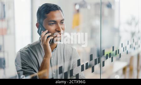Portrait of Handsome Professional Indian man nutzt Handy, spricht mit Kunden und schließt Business Deals. Erfolgreicher Mann Mit Smartphone Arbeiten Stockfoto