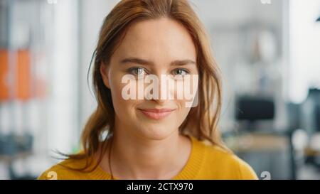 Porträt der schönen jungen Frau mit roten Haaren trägt gelbe Pullover Blick auf die Kamera und lächelt charmant. Erfolgreiche Frau, die in arbeitet Stockfoto