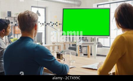 Team von Unternehmern haben ein Treffen und beobachten Green Screen Interactive Whiteboard. Junge Leute arbeiten im Creative Office. Stockfoto