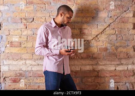 Eine ernsthafte hübscher junger Mann hält eine Tasse in einem rosa Hemd. Stockfoto