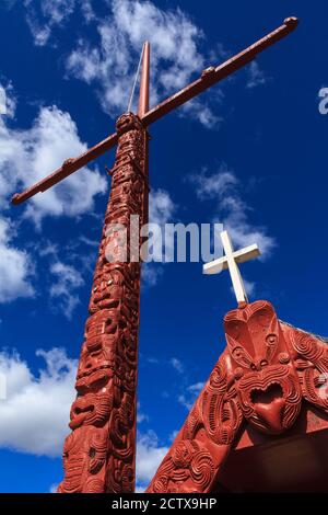 Neuseeländische Maori-Schnitzerei. Ein flagstaff und Teil eines Tagungshauses, mit einer Mischung aus traditionellen und christlichen Elementen. Rotorua, Neuseeland Stockfoto