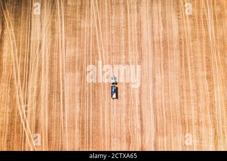 Einsamer Traktor in einem Weizenfeld während der Ernte während der Wartezeit auf den Mähdrescher. Luftaufnahme von oben Stockfoto
