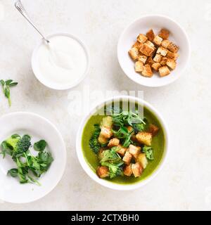 Gesunde Brokkoli grüne Erbsencremensuppe mit Croutons in der Schüssel über hellsteinarischem Hintergrund. Diätdetox-Food-Konzept. Draufsicht, flacher Lay Stockfoto