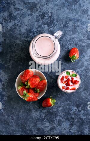 Erdbeerjoghurt mit frischen Beeren aus Glas auf blauem Steingrund. Gesundes Essen- und Getränkekonzept. Draufsicht, flacher Lay Stockfoto