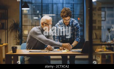 Chief Creative Designer diskutiert Designblätter mit Young Developer. Zwei Profis mit Diskussion, Arbeiten mit Dokumenten, richtige Wahl Stockfoto