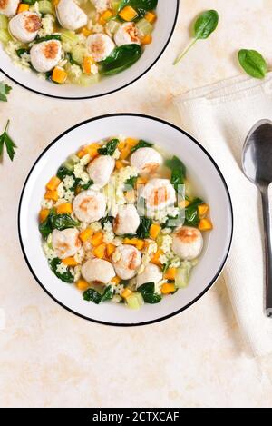 Italienische Hochzeitssuppe mit Fleischbällchen, Gemüse und kleinen Nudeln in einer Schüssel auf hellem Steingrund. Gesunde Ernährung Gericht zum Abendessen. Draufsicht, flach liegend Stockfoto