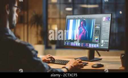 Über die Schulter: Creative Young Digital Editor arbeitet in der Bildbearbeitungssoftware auf seinem Personal Computer mit Big Display. Im Hintergrund Abend Stockfoto