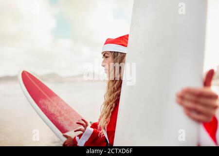 Ein Paar als weihnachtsmann am Strand mit gekleidet Ihre Surfbretter Stockfoto