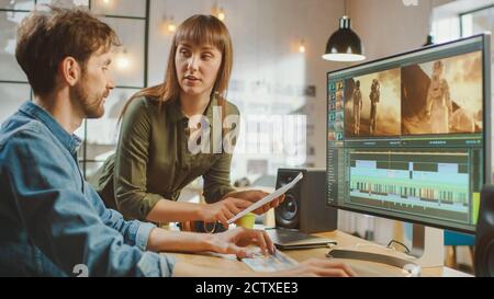 Beautiful Female Art Director konsultiert Handsome Video Editor Kollegin, sie arbeiten an einem Video-Projekt über Astronauten. Sie arbeiten in einem Cool Office Loft Stockfoto