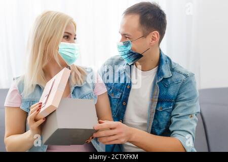 Junge romantische Liebespaar trägt eine schützende Gesichtsmaske, Pandemie und Gefühle Konzept Stockfoto