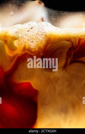 Sahne wird in Eiskaffee gegossen. Makroaufnahme, Kopierbereich. Stockfoto