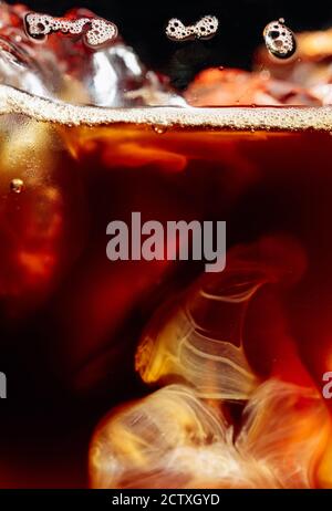 Sahne wird in Eiskaffee gegossen. Makroaufnahme, Kopierbereich. Stockfoto