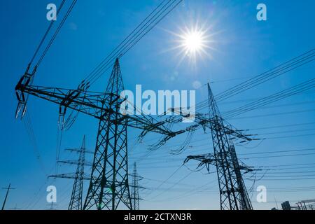 Masten und Stromleitung für Hochspannungsversorgung in Brillant beleuchtet mit Sonneneruptionen Stockfoto