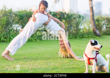 Junge Mutter und Tochter mit Hund, die an einem Sommertag Spaß im Park haben. Stockfoto