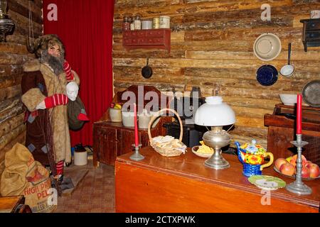 Blockhaus Innenraum, alte Möbel, rustikal, Kerzen, Kerosin Lampe, Lebensmittel, Kochgeräte Mountain man Schaufensterpuppe, schwere Mantel, Pelzhut, Bart, Natio Stockfoto