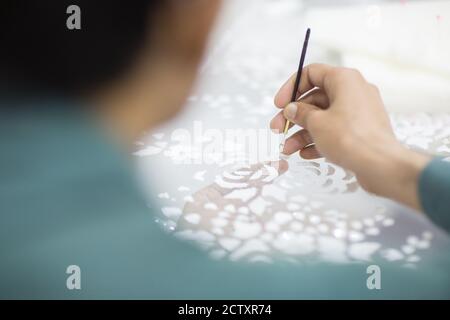 Nahaufnahme von Schneiderhandstick Perlen Muster auf einem weißen Stoff Tuch. Haute Couture Kleid machen. Stockfoto