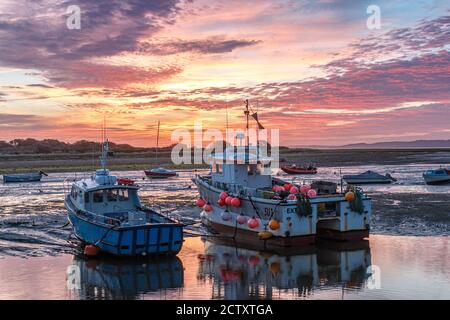 Zwei Fischerboote ruhen bei Ebbe mit dramatischem Himmel Bei Sonnenaufgang Stockfoto