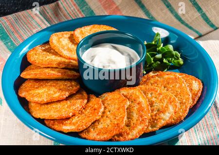 Hausgemachte Kartoffelpfannkuchen, Latkes, Draniki, Rösti oder Krapfen serviert mit Sauerrahm und Sonnenblumensprossen. Nahaufnahme Stockfoto