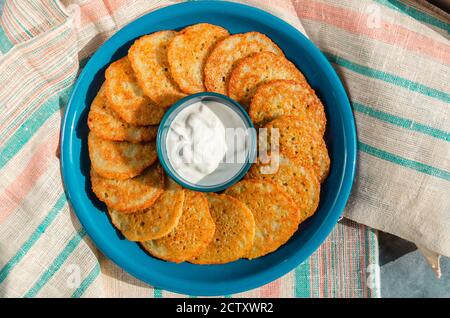 Hausgemachte Kartoffelpfannkuchen, Latkes, Draniki, Rösti oder Krapfen mit saurer Sahne serviert. Traditionelle Hanukkah-Leckereien. Draufsicht. Nahaufnahme Stockfoto