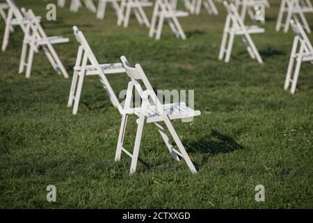 Stühle auseinander, um die soziale Distanz zu halten Während des Covid-19 Ausbruchs bei einem Outdoor-Event auf dem Gras Stockfoto