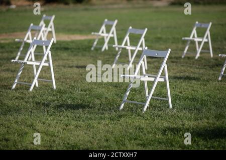 Chairs apart one from another to maintain the social distance during the Covid-19 outbreak at an outdoor event on the grass Stockfoto
