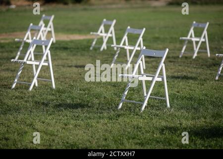 Stühle auseinander, um die soziale Distanz zu halten Während des Covid-19 Ausbruchs bei einem Outdoor-Event auf dem Gras Stockfoto