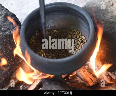 Lokal angebauter Kaffee, der über einem offenen Holzfeuer in einer schweren Eisentopf geröstet wird. Moshi, Tansania. Stockfoto