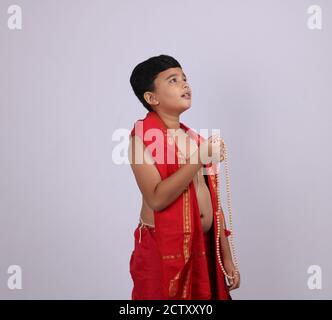 Niedlichen Jungen in indischen ethnischen tragen chanting Gottes Namen / jaap. Mit Rosenkranz Zeichenfolge Gebet Perlen oder japamala. Stockfoto