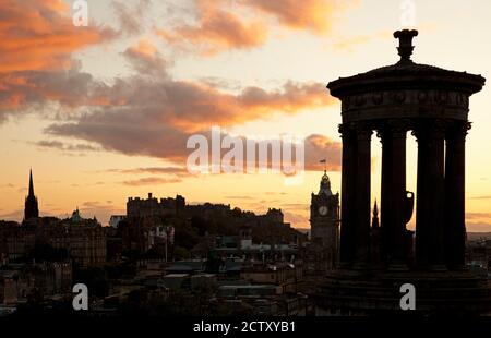 Edinburgh Stadtzentrum, Schottland, Großbritannien. 25. September 2020. Sonnenuntergang über der Stadt von Calton Hill, Temperatur 11 Grad mit einer leichten Brise. Im Bild: Dugald Stewart Monument im Vordergrund, der Hub Turm auf der linken Seite, Balmoral Hotel auf der rechten Seite und Castle in der Mitte alle sillhouetted gegen die bunten Wolken am Himmel. Stockfoto